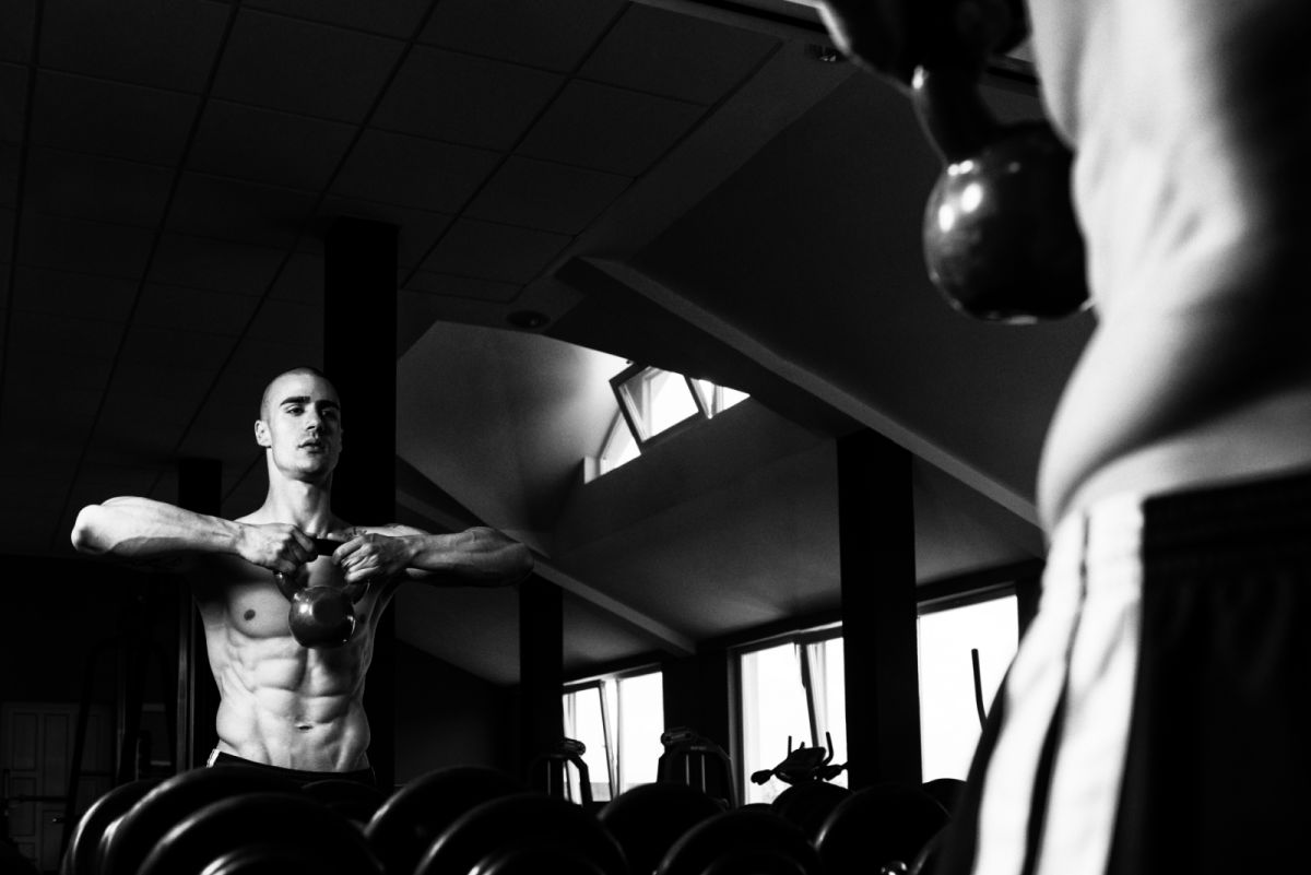 black and white picture of man with chiseled abs and kettlebell